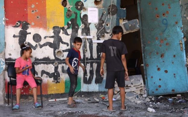 Palestinian children inspect the damage at the site of an Israeli strike on a school.